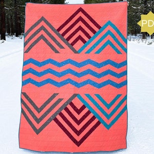 May include: A coral quilt with geometric patterns in gray, teal, and burgundy. The design includes chevron and zig-zag shapes. The quilt is shown outdoors against a snowy backdrop. A yellow PDF icon is in the upper right corner.