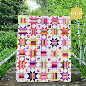 May include: A colorful quilt with a geometric pattern featuring squares, rectangles, and star shapes in shades of pink, purple, yellow, and orange. The quilt is displayed outdoors, with a "PDF" icon in the corner.