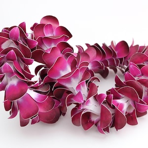 以下が含まれることがあります： ピンクの紙の花輪が2つ、それぞれ円形をしています。花輪は絡み合っており、各花の中心は白です。