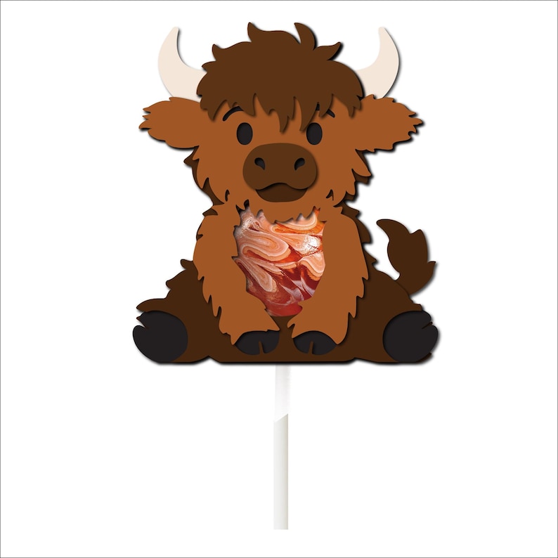 May include: A brown and black cartoon yak lollipop with a swirl lollipop inside. The yak is sitting on a white stick.
