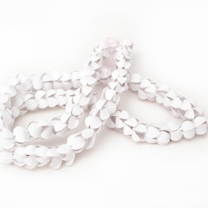 Puede incluir: Un collar de flores de papel blanco, una guirnalda hawaiana tradicional, hecha de círculos de papel en bucle.