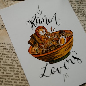 Könnte beinhalten: Eine weiße Karte mit einer handgezeichneten Illustration eines Roten Pandas in einer Schüssel mit Ramen-Nudeln. Der Text "Ramen Lovers" ist in schwarzer Kalligraphie unter der Illustration geschrieben.