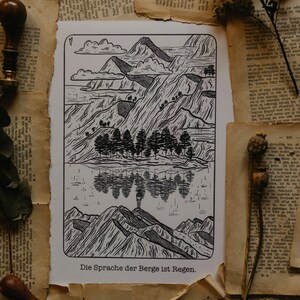 Puede incluir: Una impresi&oacute;n en madera en blanco y negro de una cordillera con un reflejo en un lago. El texto "Die Sprache der Berge ist Regen." est&aacute; en la parte inferior de la impresi&oacute;n.