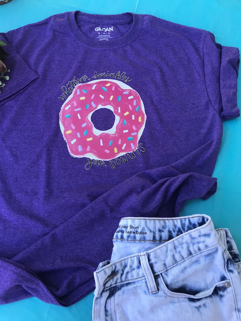 Purple graphic donut T-shirt with sprinkles designs on the donuts.