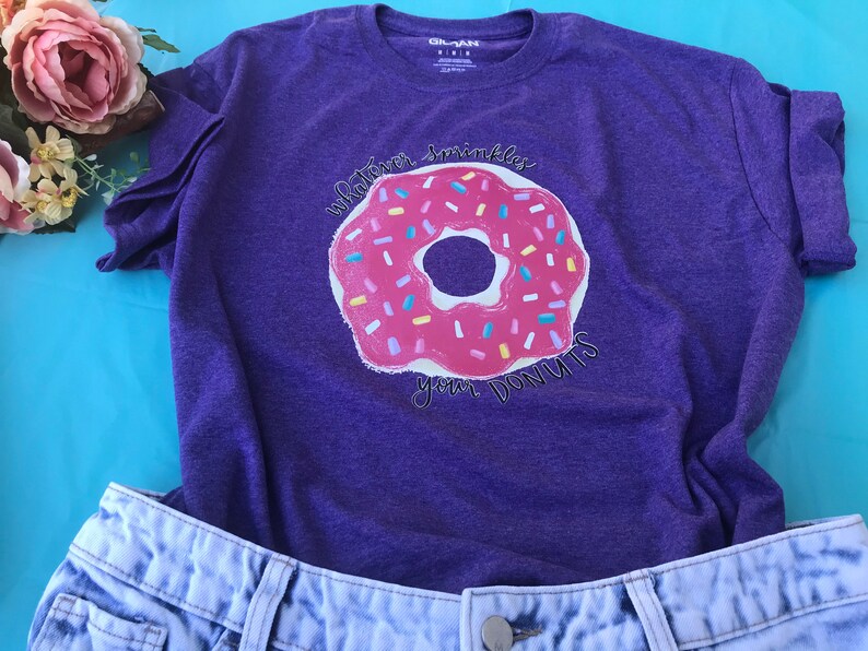 Purple graphic donut T-shirt with sprinkles designs on the donuts.