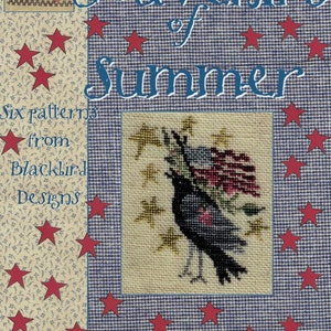 May include: A cross-stitch pattern book titled "Souvenirs of Summer" by Barl Adams & Alma Allen. The cover features a crow carrying an American flag, surrounded by red stars. The background has a blue and white checkered pattern.