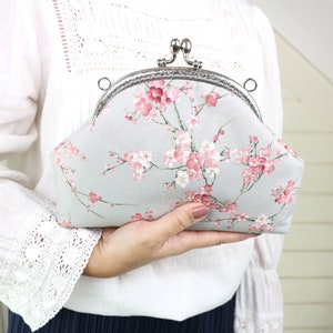 Kirschblüten Clutch mit Metall-Crossbody-Riemen. Graue Geldbörse mit rosa Sakura Blume