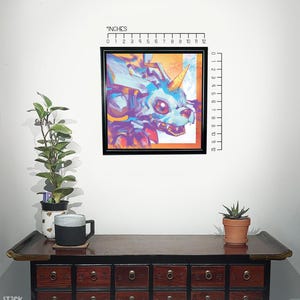 Puede incluir: Una impresi&oacute;n enmarcada de una ilustraci&oacute;n abstracta colorida de un unicornio con un esquema de color azul y morado. La impresi&oacute;n mide 12 pulgadas por 12 pulgadas y se muestra en una pared con una regla para la escala.