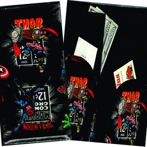 May include: Black wallet with a comic book design featuring Thor, Black Widow, and Captain America. The wallet has a pocket for cash and cards.