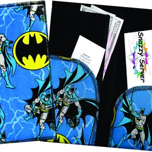 May include: A blue and black fabric wallet with a Batman theme. The wallet has a flap with a black fabric interior. The wallet has a Snazzy Server logo on the front.