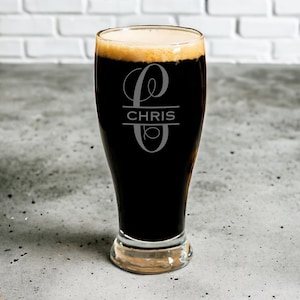 May include: A personalized beer glass with a dark beer inside. The glass has a monogram with the letter "C" and the name "CHRIS" etched on it.