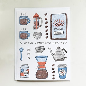 May include: A greeting card with coffee-themed illustrations. The card features drawings of coffee cups, a French press, a bag of coffee beans, a pour-over coffee maker, and a milk carton. The text "A LITTLE SOMETHING FOR YOU" is also included.