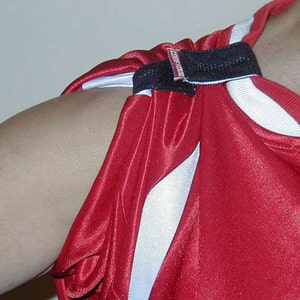 May include: A red and white athletic jersey with a black strap across the shoulder. The strap has the text "Teamwork" printed on it.
