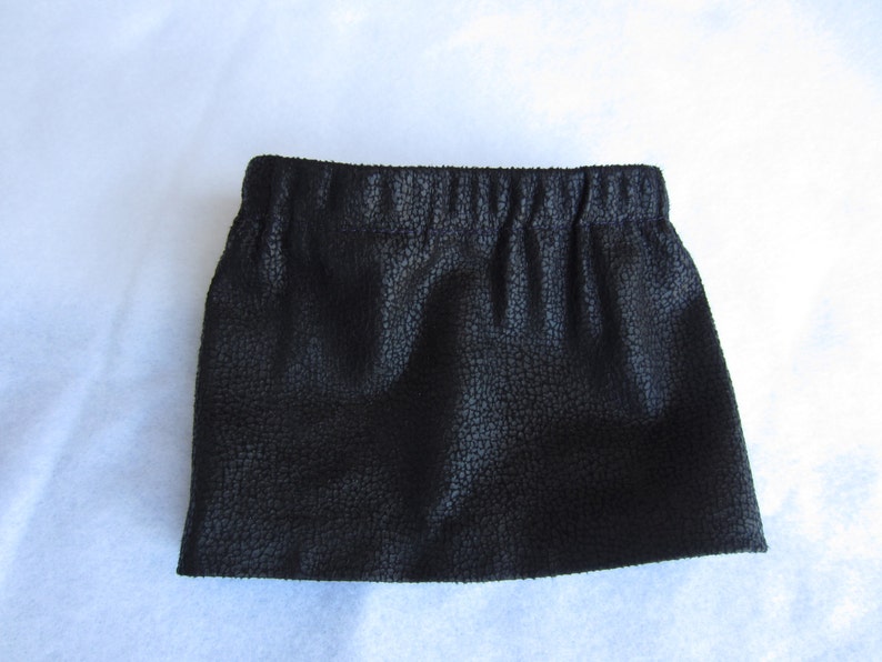 May include: A black faux leather skirt with a textured surface and an elastic waistband.