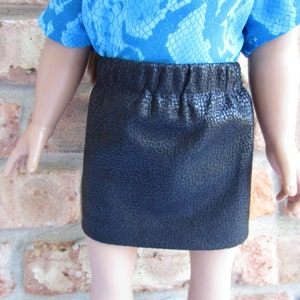 May include: A black faux leather skirt with a textured surface. The skirt has a waistband and is about knee-length.