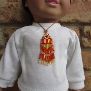 May include: A white shirt with a beaded necklace featuring orange, pink, and gold beads. The necklace is a long, dangling style with a tassel at the bottom.