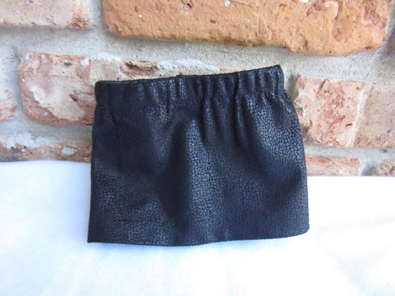May include: A black faux leather skirt with a gathered elastic waistband.