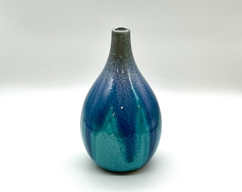 May include: A blue and green ceramic vase with a rounded bottom and a narrow neck. The vase has a mottled glaze with streaks of blue and green.