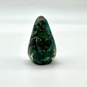 May include: A teardrop-shaped, green and gold resin paperweight with a unique, mosaic-like design.