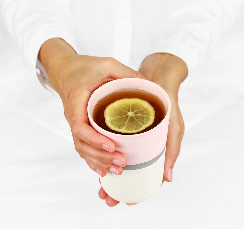 Pu&ograve; includere: Una tazza in ceramica rosa e bianca con una fetta di limone che galleggia in una tazza di t&egrave;.