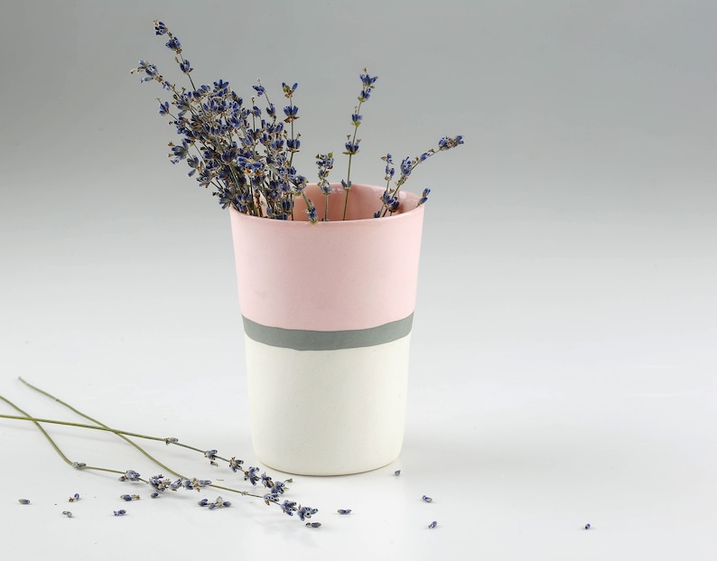 Pu&ograve; includere: Un vaso in ceramica rosa e bianco con una striscia grigia intorno al centro, pieno di fiori di lavanda secchi.