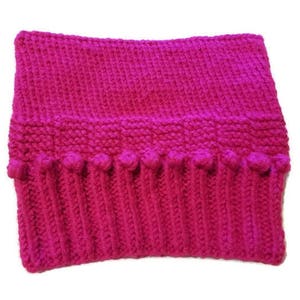 May include: A vibrant fuchsia-colored knitted cowl. The cowl features a ribbed bottom section with small bobbles, a textured middle section, and a smooth top. This handmade accessory is perfect for staying warm in cold weather.