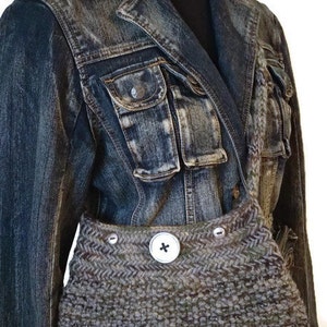 May include: A brown and gray knitted bag with a large button closure. The bag is worn over a denim jacket.