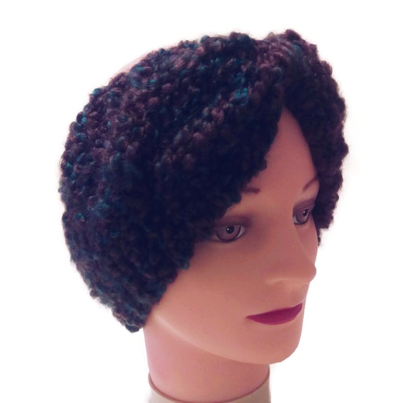 May include: A brown and teal knitted headband with a fuzzy texture. The headband is worn on a mannequin's head.