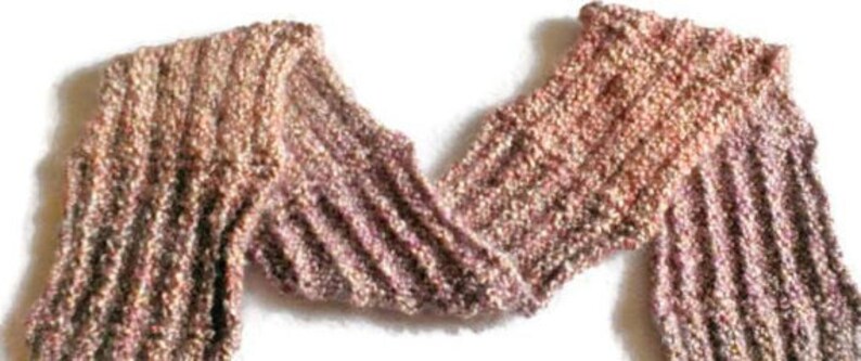 Op de afbeelding: Een zachte, gebreide sjaal in tinten roze, bruin en beige. De sjaal is gemaakt met een textuur-steek en heeft een lang, vloeiend ontwerp.
