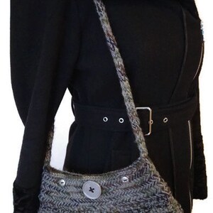 May include: A black coat with a fur collar and a gray knitted bag with a button closure. The bag is worn over the shoulder.