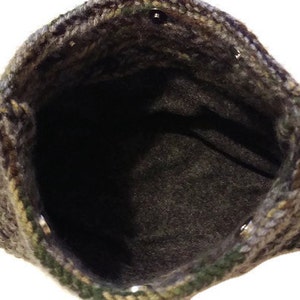 May include: A crocheted bag with a camouflage pattern and a brown lining. The bag has two handles and a button closure.