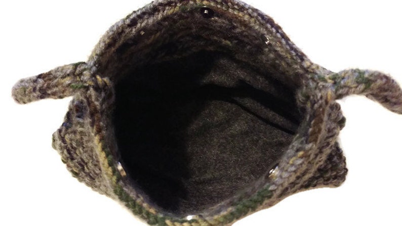 May include: A crocheted bag with a camouflage pattern and a brown lining. The bag has two handles and a button closure.