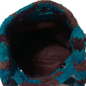 May include: A teal and brown crocheted tote bag with a brown fabric lining. The bag is empty and the inside is visible.