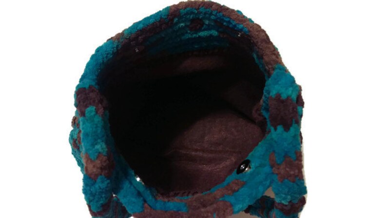 May include: A teal and brown crocheted tote bag with a brown fabric lining. The bag is empty and the inside is visible.