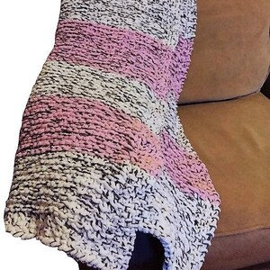 May include: A soft, chunky knit throw blanket with stripes of pink and white on a brown background.