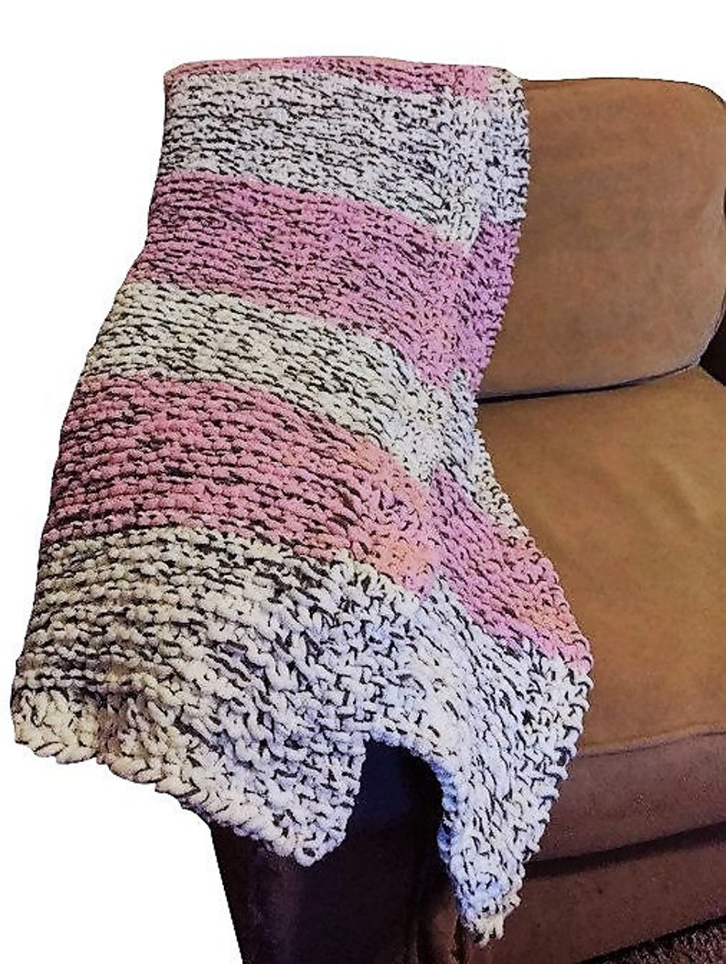 May include: A soft, chunky knit throw blanket with stripes of pink and white on a brown background.