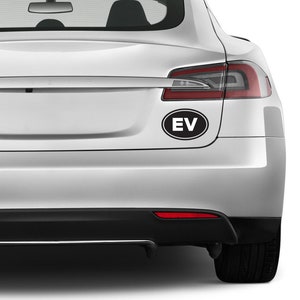 May include: A silver car with a black oval sticker that says "EV" on the back bumper.