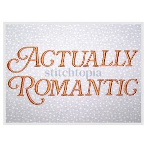 May include: A white fabric with a light gray polka dot pattern. The words "ACTUALLY ROMANTIC" are embroidered in a copper-colored script font. The word "stitchtopia" is in a smaller, light blue font.