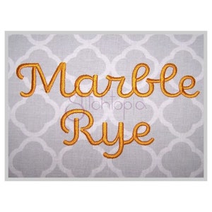 May include: Embroidered name in a cursive font, the name is "Marble Rye" in gold thread on a gray background.
