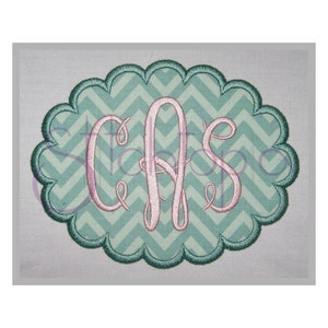 May include: A monogram with the letters "CAS" in pink embroidery on a teal chevron background. The monogram is surrounded by a scalloped border.