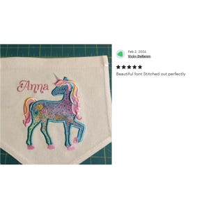 May include: A personalized embroidered tote bag with a colorful unicorn design and the name "Anna" stitched in pink.