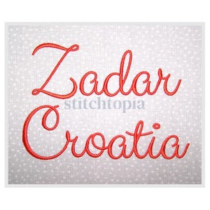 May include: A white fabric square with a red embroidered design. The design features the word "Zadar" above "Croatia" in a cursive font. The word "stitchtopia" is in a smaller font between the two words.