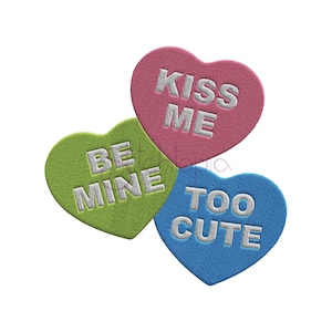 May include: Three heart-shaped candy conversation hearts with the phrases "Kiss Me", "Be Mine", and "Too Cute" in white lettering.