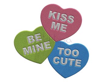 Puede incluir: Tres corazones de caramelo en forma de corazón con las frases "Kiss Me", "Be Mine" y "Too Cute" en letras blancas.