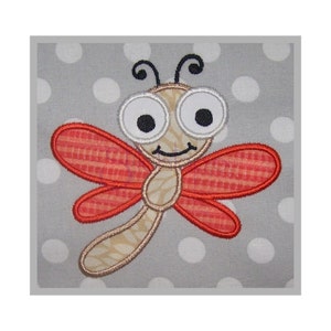 May include: A red and white embroidered dragonfly with large, white eyes and a smiling mouth. The dragonfly is on a gray background with white polka dots.