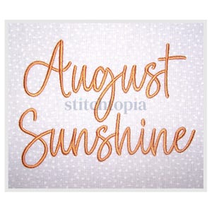 Puede incluir: Texto bordado « August Sunshine » en naranja dorado sobre tela blanca con estampado de lunares. La fuente es cursiva y elegante. También se ve el nombre de la marca « stitchtopia ».