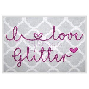 Può includere: Disegno ricamato con filo rosa su uno sfondo di tessuto grigio. Il disegno dice "Amo il glitter" con un simbolo di cuore prima e dopo la parola "amo".