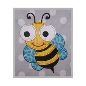 May include: Embroidered bee applique with large white-rimmed eyes, black antennae, and a smiling red mouth. The bee has yellow and black striped body, blue patterned wings, and a black stinger. The background is gray with white polka dots.