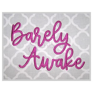 May include: Embroidered design on a gray fabric background. The design is in pink cursive lettering and reads "Barely Awake".