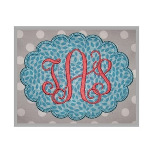 May include: A teal blue scalloped oval frame with a white leaf pattern. The frame contains a red embroidered monogram of the letters "AS".